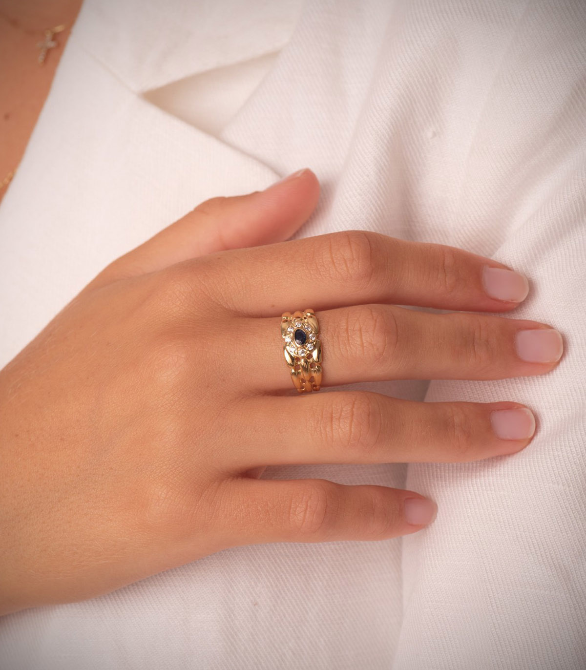 Bague en or sertie d'une pierre saphir bleue portée à la main