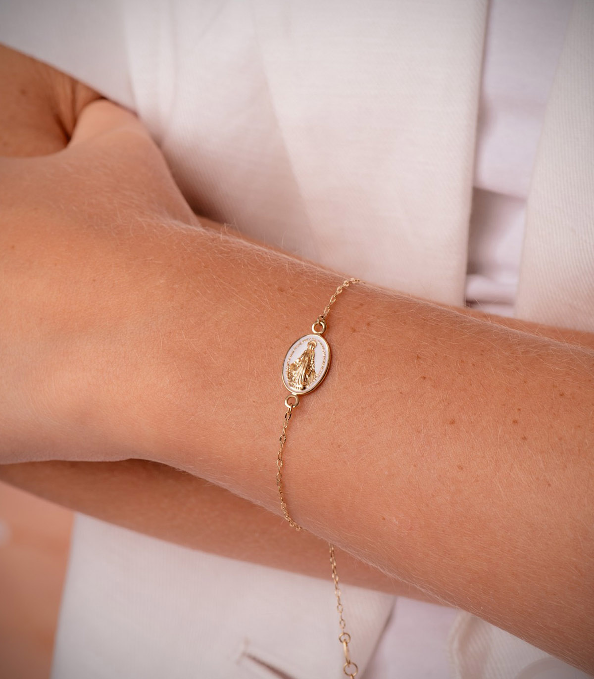 Bracelet fin en or avec médaille de la Vierge Marie porté au poignet